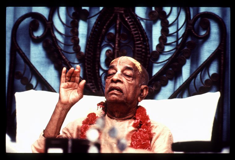 A teacher giving a spiritual discourse surrounded by flowers